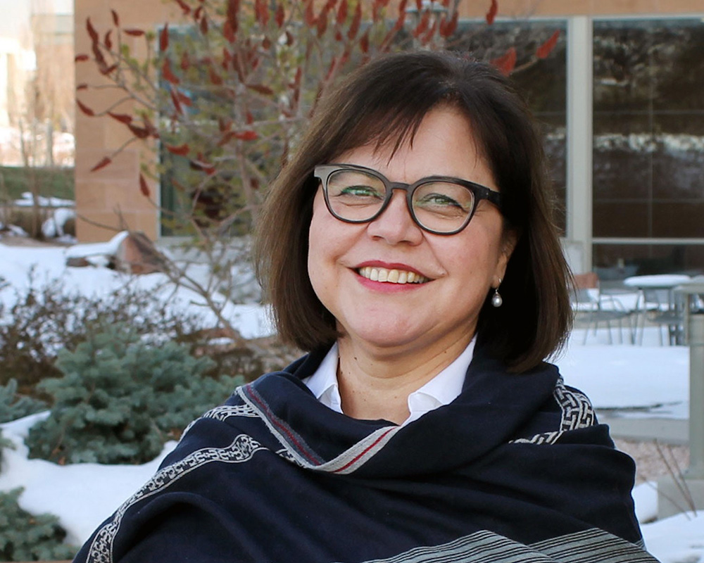 Headshot of Isabel smiling at the camera with a snow background