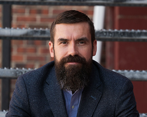 Headshot of Chris Low looking at the camera with a small closed smile.